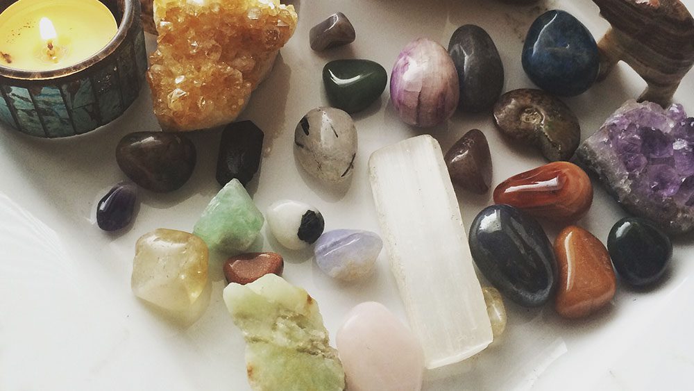 Assortment of rocks and crystals on table with candle burning