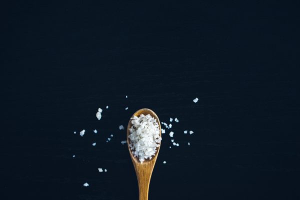 wooden teaspoon with course sea sat. Dark background