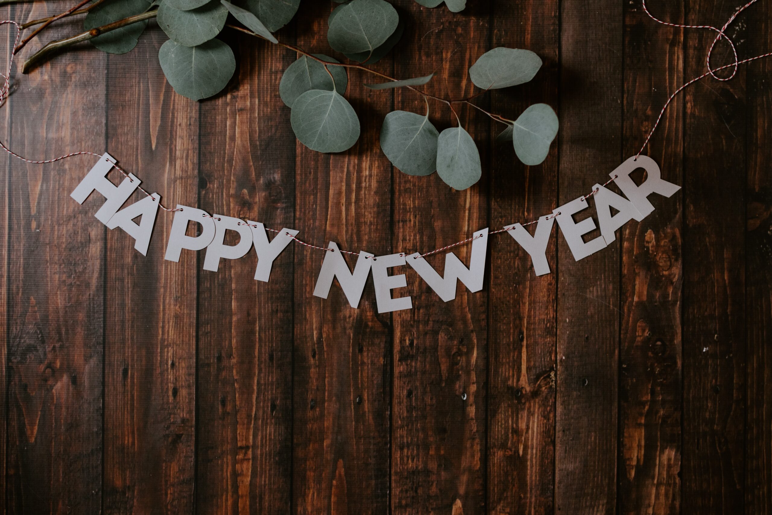 Cutout letters strung together spelling "happy new year." Banner resting on wooden table