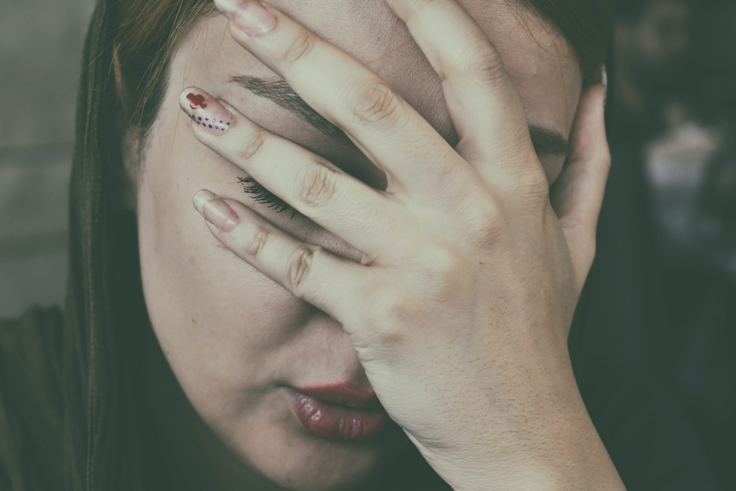 Person with migraine. Their head is downturned and resting in their hand