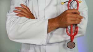 doctor in a lab coat holding a red stethoscope