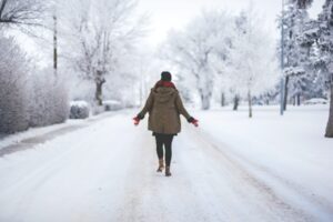 Person on a walk in winter down a dirt road.