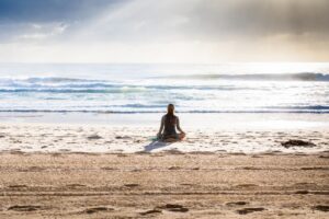 Person meditating in distance on a beach 