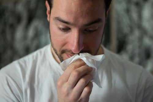 Man blowing nose with tissue