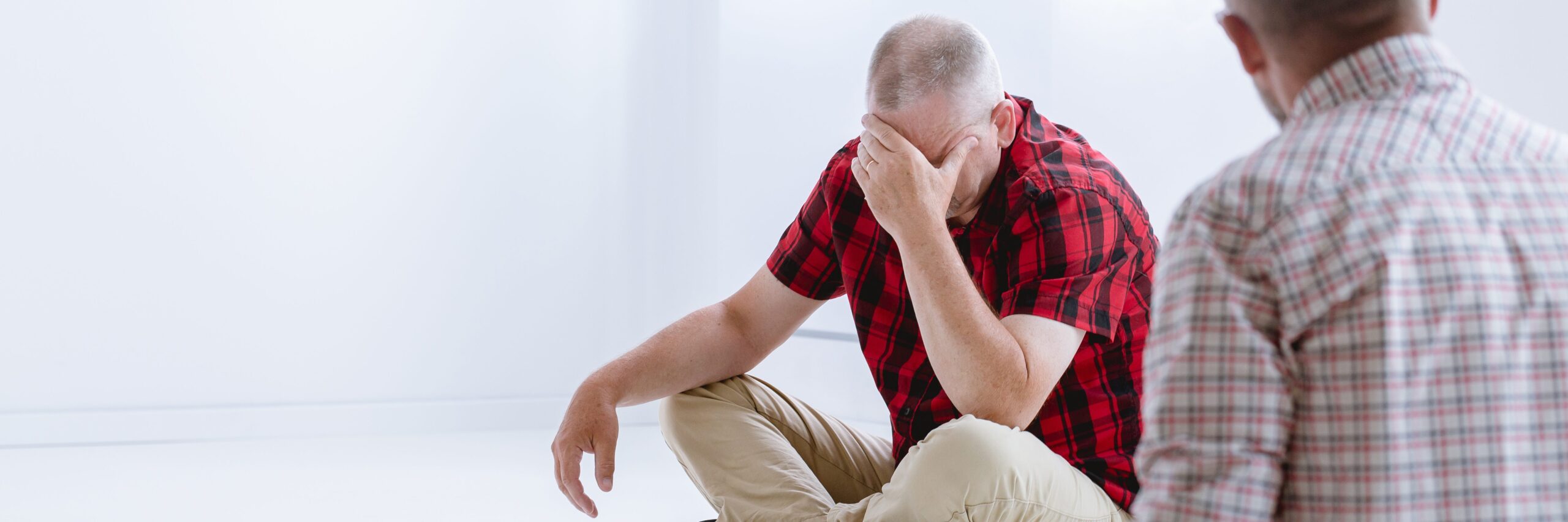 2 people sitting together. One has his head in his hand indicating sadness or stress