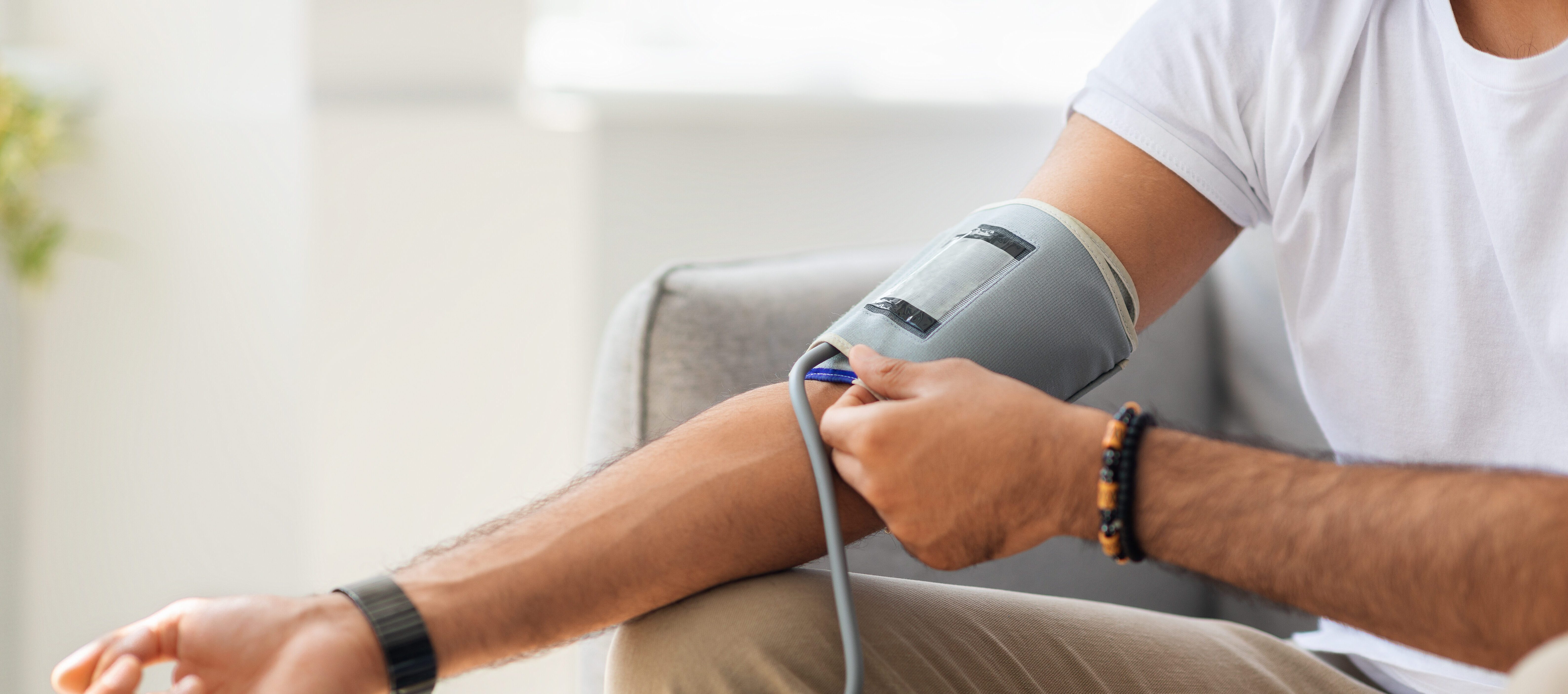 Patient checking blood pressure with blood pressure monitor and cuff