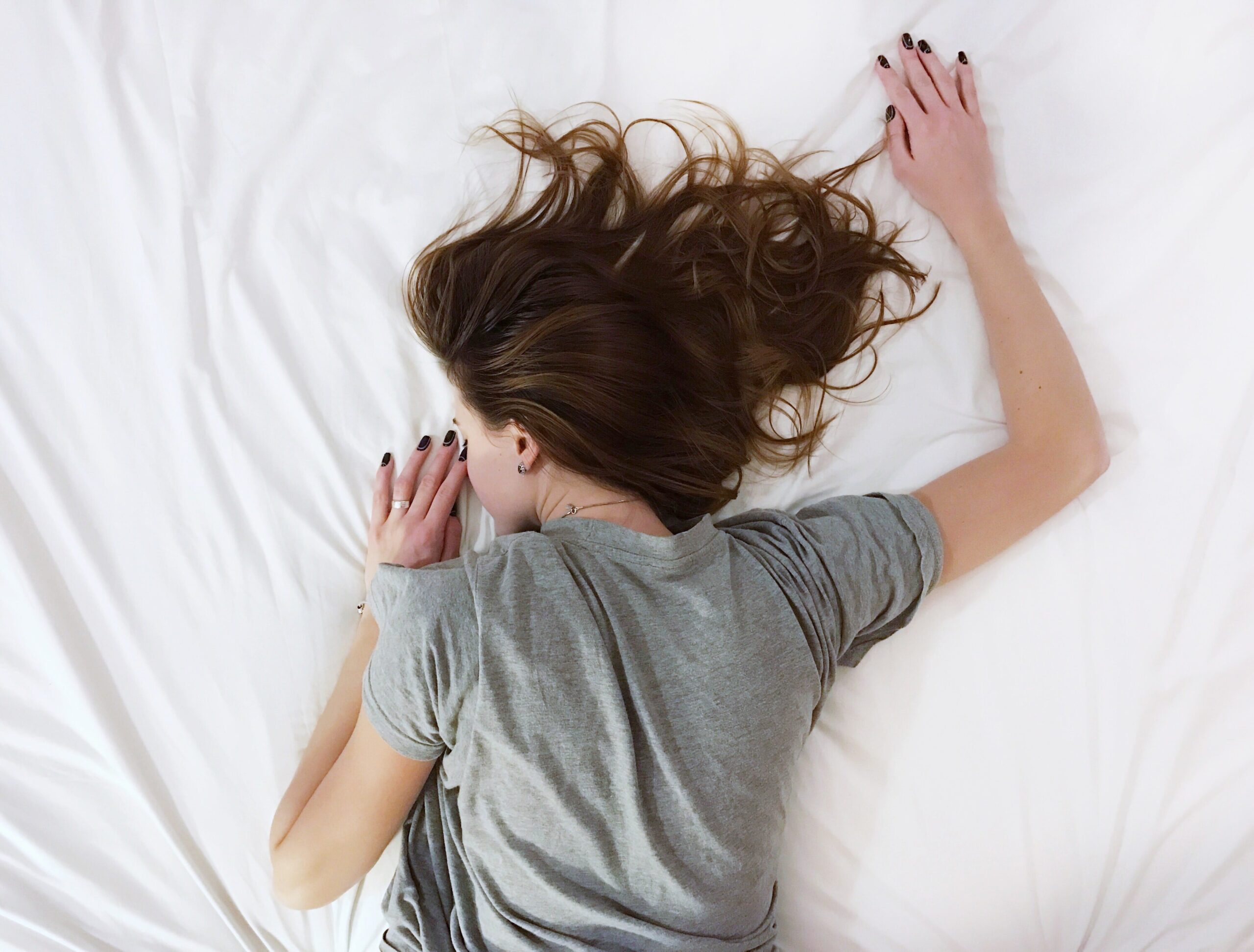 Sleeping with arms outstretched on white sheets